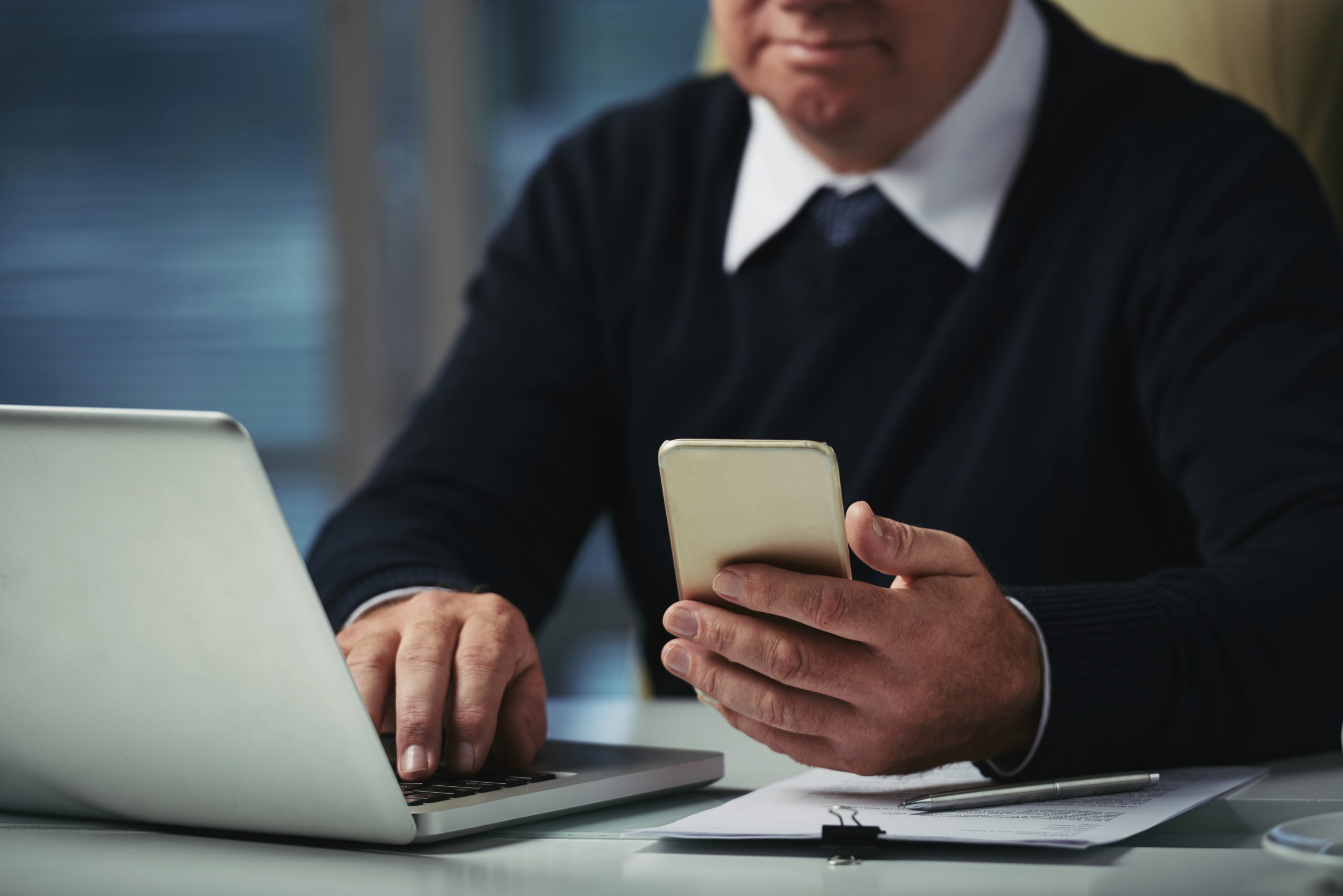 cropped-man-checking-messages-his-phone-office-scaled.jpg