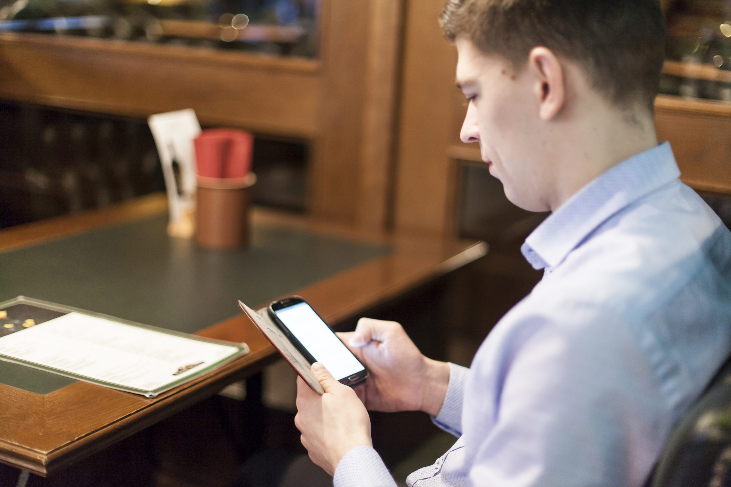 man-browsing-smartphone-restaurant-scaled.jpg